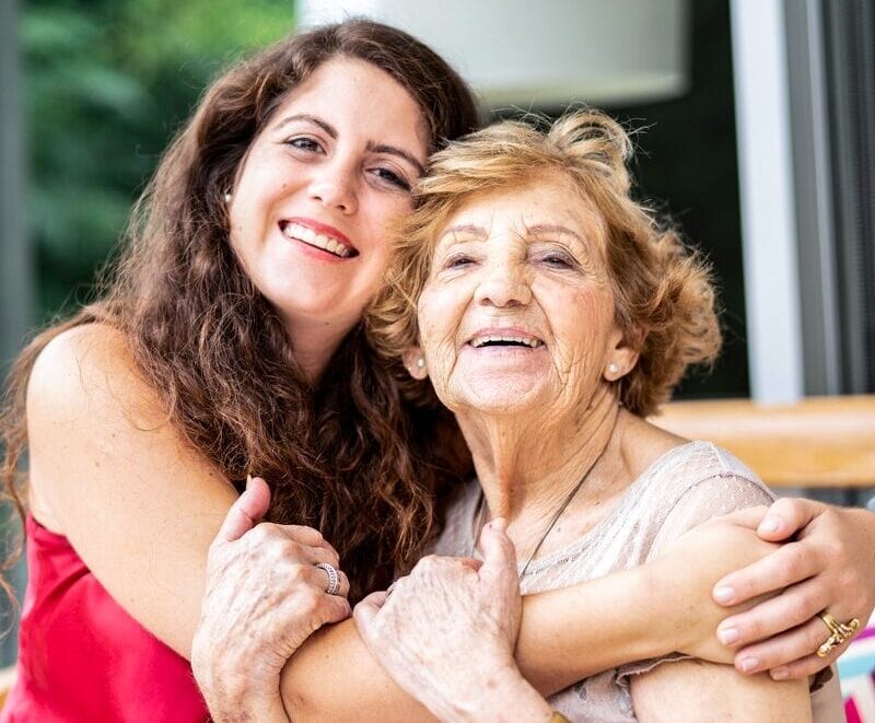 Courtyard Care Giver giving a hug to a senior resident