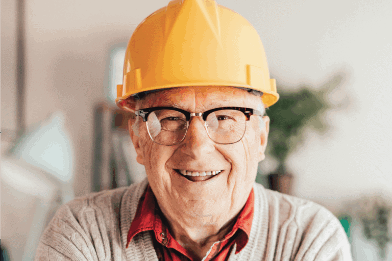 Senior man smiling with a yellow hard hat on