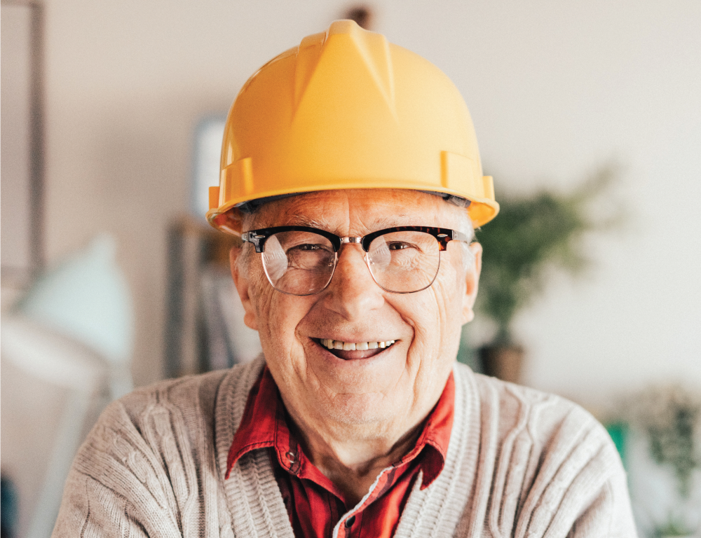 Senior man smiling with a yellow hard hat on