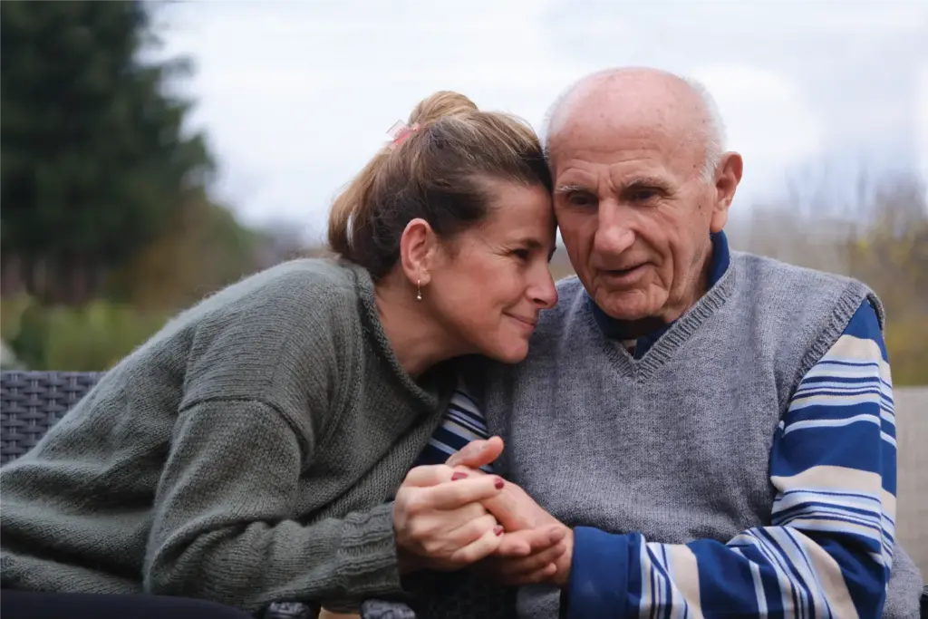 adult daughter and father sitting on a park bench