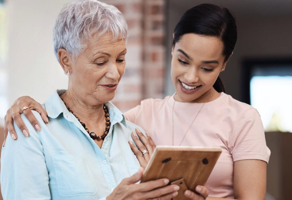Senior woman and adult daughter looking at an iPad looking into downsizing