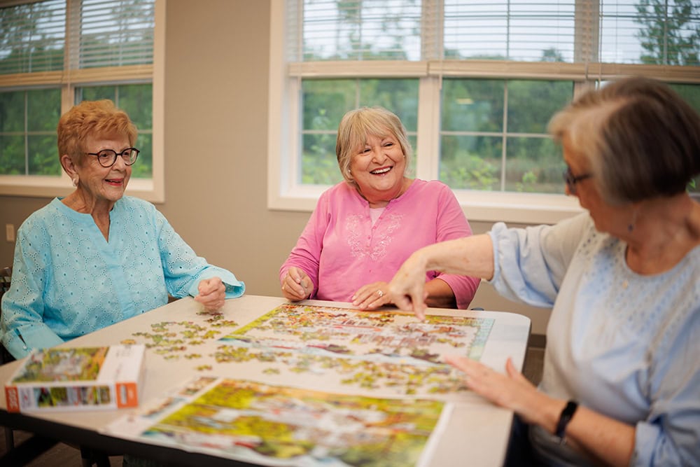 Group of assisted living residents working on a puzzle together.