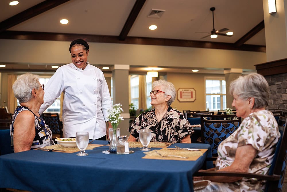 Dining room chef chatting with three residents